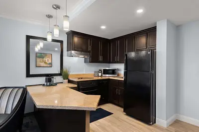 a kitchen with a black refrigerator and wooden cabinets at City Express by Marriott Manhattan Beach in Manhattan Beach