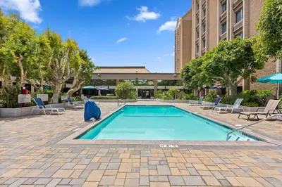 a swimming pool in a courtyard with chairs and a building at Doubletree by Hilton Whittier in Whittier