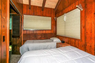 two beds in a room with wood walls and windows at Lakeview Fishing House-121 by Big Bear Vacations in Big Bear Lake