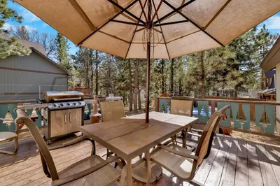 a wooden table and chairs with an umbrella on a deck at Moose Creek Chalet-1237 by Big Bear Vacations in Big Bear Lake