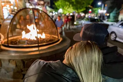 a man and a woman sitting next to a fire fountain at Mountain Modern-1743 by Big Bear Vacations in Big Bear Lake