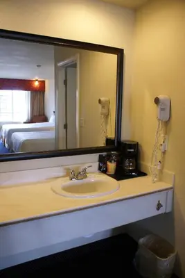 a bathroom with a sink and a large mirror at Queens Inn Anaheim in Anaheim