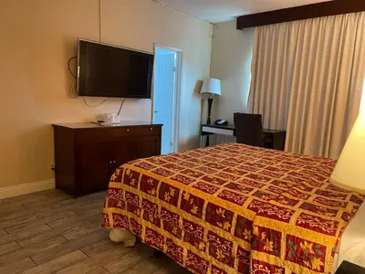 a hotel room with a bed and a flat screen tv at Grand Inn in Fullerton