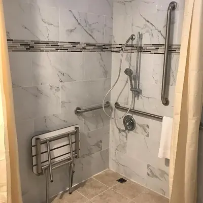 a shower in a bathroom with white marble walls at Grand Inn in Fullerton