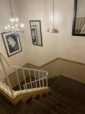 a staircase with a chandelier and pictures on the wall at Grand Inn in Fullerton