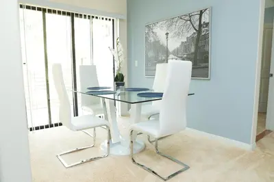 a dining room with a glass table and white chairs at Amazing Apartments near the grove in Los Angeles