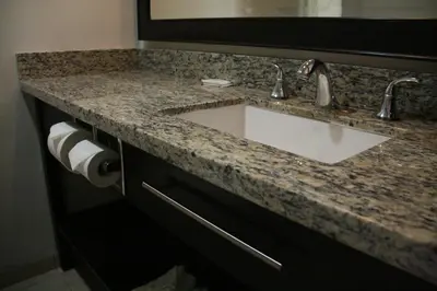a bathroom with a sink and a granite counter top at Motel 6 Monterey Park in Monterey Park