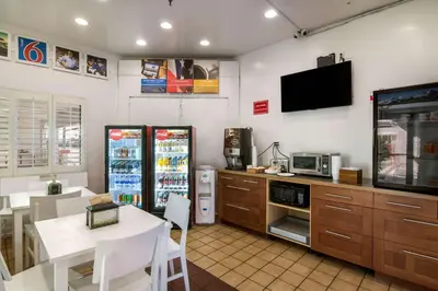 a kitchen with a refrigerator and a table and a tv at Motel 6 Monterey Park in Monterey Park