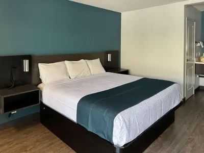 a bedroom with a large bed with a blue wall at Studio 6 Suites Gardena, CA in Gardena