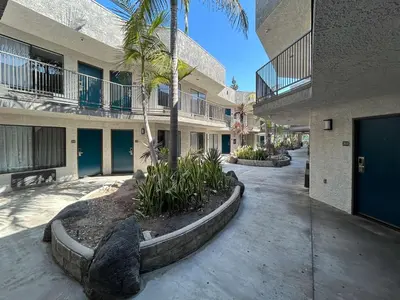 a courtyard of a building with a palm tree and a sidewalk at Studio 6 Suites Gardena, CA in Gardena