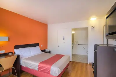 a hotel room with a bed with an orange wall at Motel 6-Camarillo, CA in Camarillo