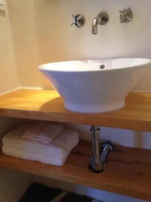 a white sink on a wooden shelf with towels at Under the Tuscan Sun Cottage in West Los Angeles in Los Angeles