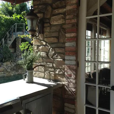 a stone wall with a lamp on a table next to a window at Under the Tuscan Sun Cottage in West Los Angeles in Los Angeles