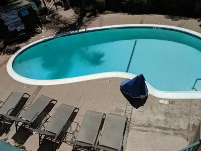 an overhead view of a swimming pool with chairs and an umbrella at Tarzana Inn in Tarzana