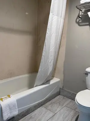 a bathroom with a tub and a toilet with a shower curtain at Days Inn by Wyndham Ontario Airport in Ontario