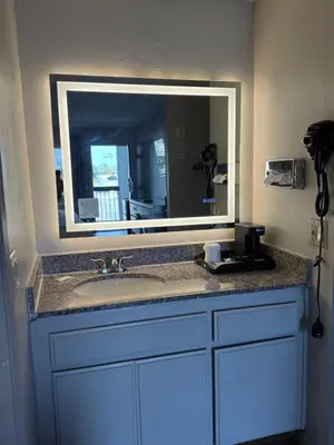 a bathroom with a sink with a large mirror at Days Inn by Wyndham Ontario Airport in Ontario