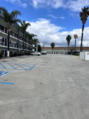 a parking lot in front of a building with palm trees at Days Inn by Wyndham Ontario Airport in Ontario