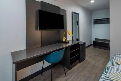 a bedroom with a desk with a tv and a bed at Motel 6-Fontana, CA in Fontana
