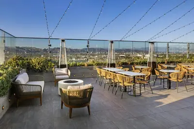 a patio with tables and chairs on a roof at AC Hotel by Marriott Beverly Hills in Los Angeles