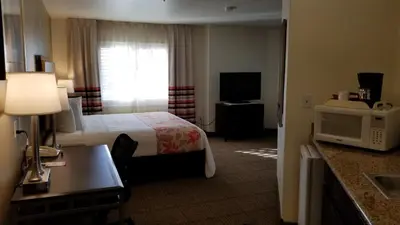 a hotel room with a bed and a television at Hawthorn Suites in Victorville