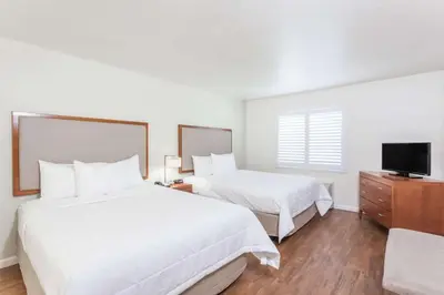 a hotel room with two beds and a flat screen tv at Hawthorn Suites in Victorville