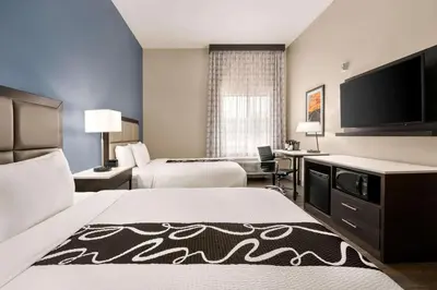 a hotel room with two beds and a flat screen tv at La Quinta Inn & Suites by Wyndham San Bernardino in San Bernardino