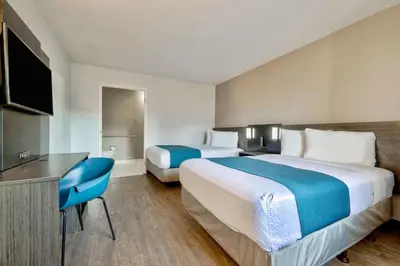 a hotel room with two beds and a desk at Motel 6-Anaheim, CA - Fullerton East in Anaheim