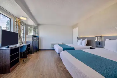 a hotel room with two beds and a flat screen tv at Motel 6-Anaheim, CA - Fullerton East in Anaheim