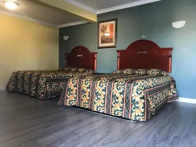 two beds in a room with green walls at Colony Inn Motel in Bellflower