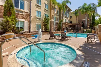 a hot tub in a courtyard with chairs and a building at Comfort Inn & Suites Near Ontario Airport in Ontario