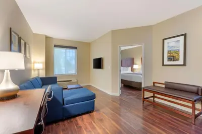 a living room with a blue couch and a bed at Comfort Inn & Suites Near Ontario Airport in Ontario