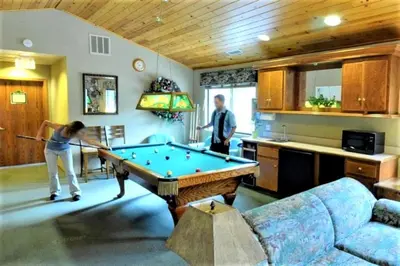 a woman playing a game of pool in a living room at Lagonita Lodge in Big Bear Lake