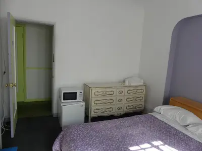 a bedroom with a bed and a dresser and a microwave at Wilshire Orange Hotel in Los Angeles