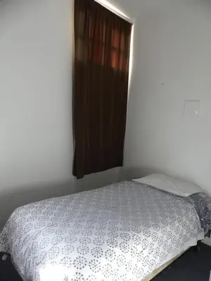 a bed in a white room with a window at Wilshire Orange Hotel in Los Angeles