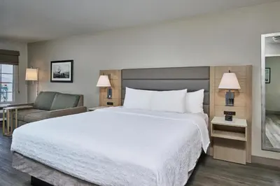 a hotel room with a large bed and a chair at Hampton Inn & Suites Hermosa Beach in Hermosa Beach