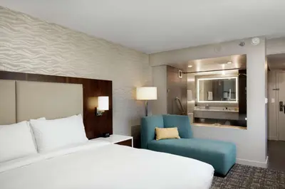 a hotel room with a bed and a blue chair at DoubleTree by Hilton Monrovia - Pasadena Area in Monrovia