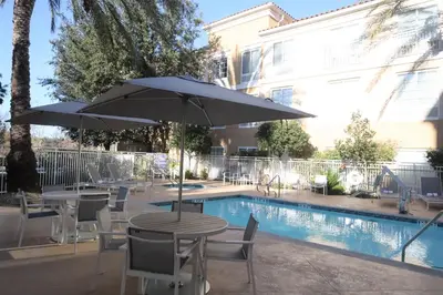 a table and chairs with an umbrella next to a pool at Hilton Garden Inn Calabasas in Calabasas