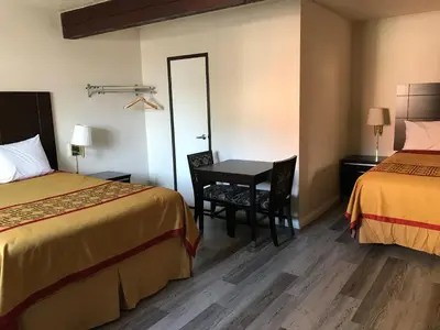 a hotel room with two beds and a table and chairs at Manhattan Inn & Suites in Manhattan Beach