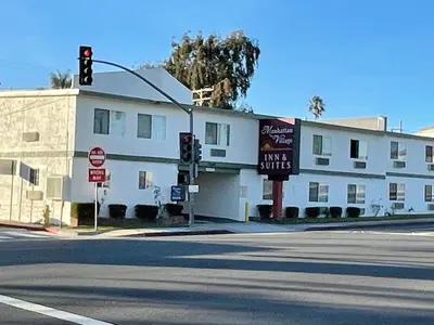 a white building on a street corner with a traffic light at Manhattan Inn & Suites in Manhattan Beach