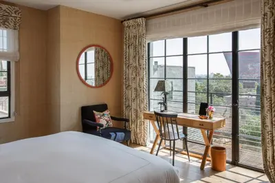 a bedroom with a bed and a desk and windows at Hotel 850 SVB, West Hollywood, a Member of Design Hotels in Los Angeles