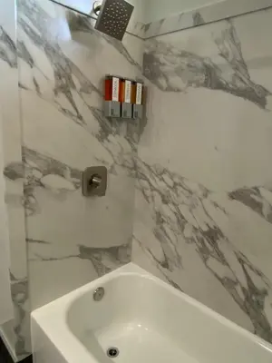 a bathroom with a shower and a tub and a sink at Harbor Inn in Harbor City