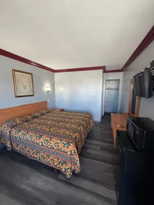 a hotel room with a bed and a flat screen tv at Harbor Inn in Harbor City