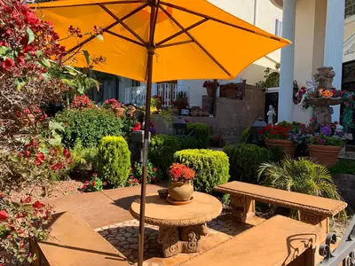 a yellow umbrella sitting on a table in a garden at Entire Second Flr - Santa Monica Luxury Roman Villa in Los Angeles