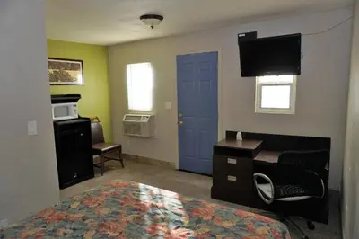 a room with a bed and a desk and a blue door at Route 66 Motel - Rialto in Rialto