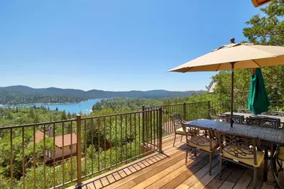 a deck with a table and chairs and an umbrella at Mountain Top Chalet in Lake Arrowhead