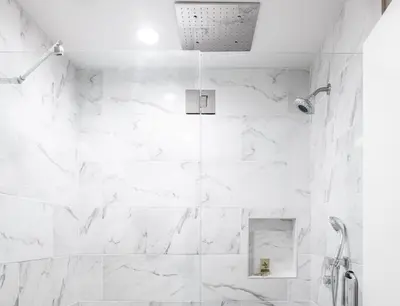 a bathroom with a shower with white marble walls at Route 66 Motel in Barstow