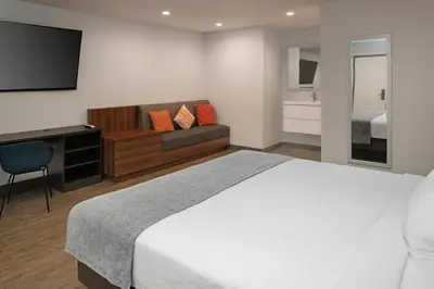 a bedroom with a bed and a couch and a television at Route 66 Motel in Barstow