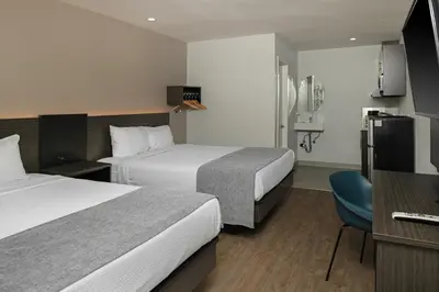 a hotel room with two beds and a television at Route 66 Motel in Barstow