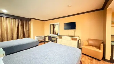 a hotel room with two beds and a chair at Redondo Beach Inn-LAX in Gardena