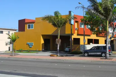 a yellow building with palm trees in front of a street at Redondo Beach Inn-LAX in Gardena